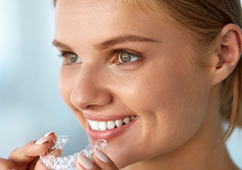 Female holding clear aligners